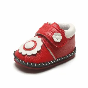 Gros plan chaussures bébé rouges à semelle souple et détail fleur