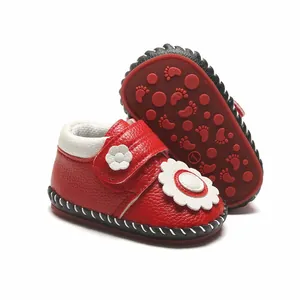 Détail de chaussures premier pas rouges pour bébé avec semelle souple et fleurs