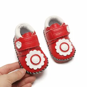 Détail de chaussures de marche bébé rouges avec fleur blanche et semelle en caoutchouc