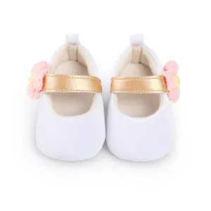Close-up of white baby girl princess pre-walker shoes with gold strap and pink flower