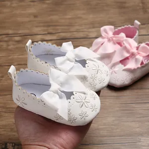 Detailansicht weißer Baby-Prinzessinenschuhe mit Schleife und Blumenstickerei
