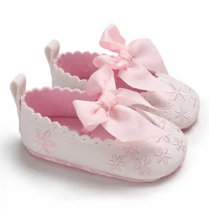 Nahaufnahme von rosa Baby-Prinzessin-Schuhen mit Schleifen und Blumenstickerei