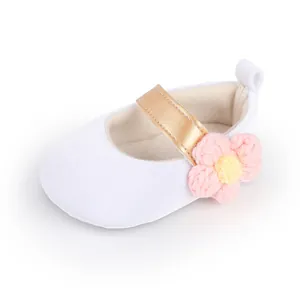 Detail showing the crocheted pink flower and gold strap on white baby girl shoes.