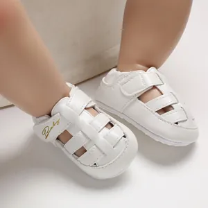 Detailed view of white leather baby closed-toe walking sandals with Baby gold embroidery.