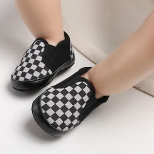 Close-up view of checkerboard pattern baby slip-on shoes with soft soles on feet