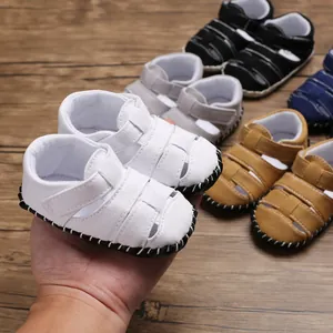 Primo piano di sandali da camminata per neonati in tela bianca con velcro tenuti in mano.