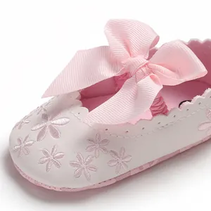 Detaillierte Nahaufnahme eines rosa Baby-Prinzessinenschuhs mit Schleife und Stickerei.