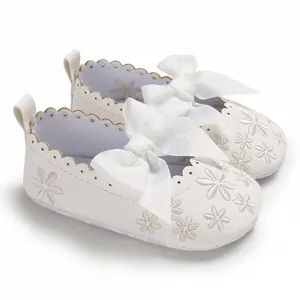 Detailansicht der weißen Baby-Prinzessin-Schuhe mit Seidenschleife und Blumenstickerei