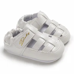 Close-up of white baby walking sandals with gold Baby script and cutout design.