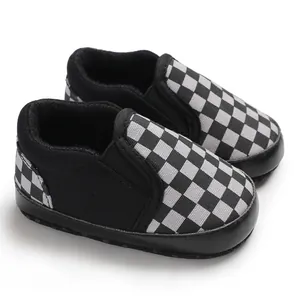 Detail view showing the black and grey checkerboard pattern on soft-soled baby shoes