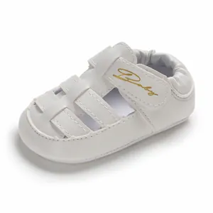 Detailed macro view of white summer closed-toe baby sandals with gold Baby logo on strap