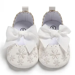 Detailansicht eleganter weißer Babyschuhe mit großer Schleife und Blumenstickerei