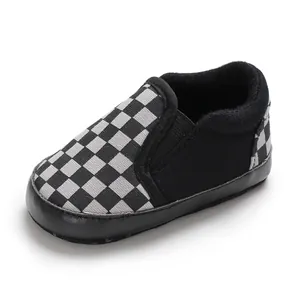 Close-up of black and white checkerboard soft-soled infant pre-walker shoes for babies