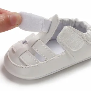 Close-up view of the adjustable hook-and-loop strap closure on a white baby sandal