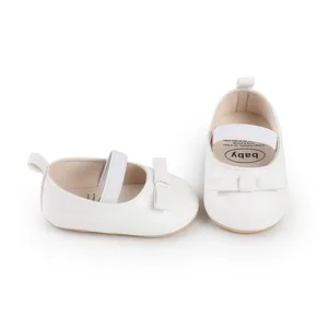 Gros plan de chaussures de cérémonie pour bébé blanches avec nœud papillon et bride élastique