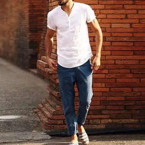Mannequin portant une chemise en lin blanc décontractée avec col montant et pantalon bleu.