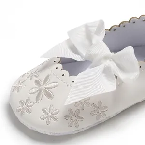Detailansicht der floralen Stickerei und der weißen Schleife an einem Baby-Prinzessin-Schuh