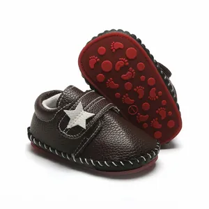 Détail de chaussures de marche pour bébé marron avec étoile blanche et semelle rouge