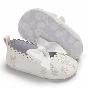 Detail der weißen Baby-Prinzessin-Schuhe mit Blumenstickerei und Kirschmuster-Sohle.