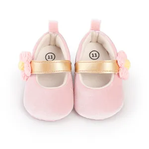 Close-up of pink velvet baby girl Mary Jane shoes with gold strap and flower detail