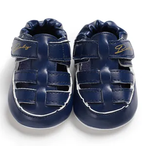 Detailed view of navy blue closed-toe baby sandals with a golden Baby logo print