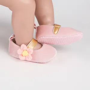 Close-up of pink baby girl princess walking shoes with decorative flower and gold strap