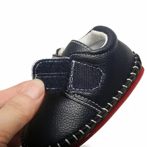 Détail montrant la sangle velcro réglable sur une chaussure de marche bleu marine pour bébé.