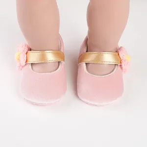 Close-up of pink baby walking shoes with golden straps and crochet flower detail