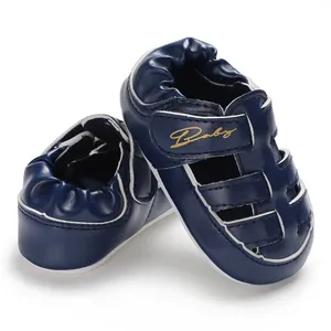 Detail view of navy blue baby sandals with gold Baby embroidery and non-slip sole