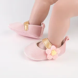 Close-up detail showing pink velvet baby girl walker shoes with a cute knitted flower