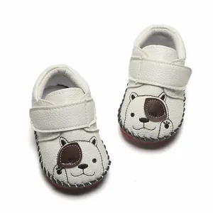 Gros plan de chaussures de marche blanches pour bébés avec motif chiot et semelles souples