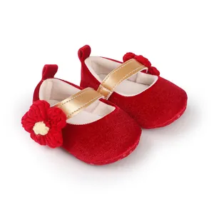 Detailed view of red velvet baby princess shoes with knitted flower decoration.