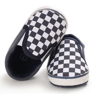 Close-up detail of the classic black and white checkerboard pattern on slip-on baby shoes