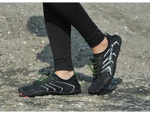 Dettaglio ravvicinato di scarpe da scoglio nere antiscivolo con lacci verdi su roccia