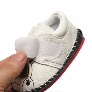 Vue détaillée de chaussures pour bébé en cuir blanc avec fermeture velcro