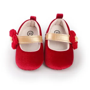 Detailed view of red velvet baby shoes with gold straps and flower decor.