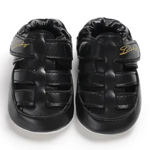Close-up detail of black leather baby sandals with gold Baby script on the strap