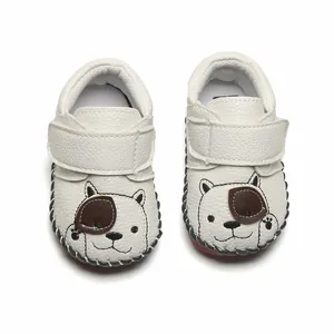 Gros plan de chaussures de marche pour bébé blanches avec broderie chien mignonne.