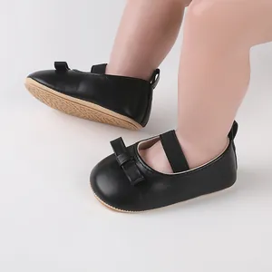 Gros plan de chaussures de marche noires pour bébés filles avec nœud et semelle en caoutchouc