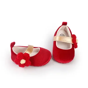 Adorable red velvet baby walking shoes featuring a gold strap and a knitted flower ornament