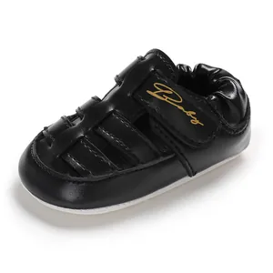 Detail view of a stylish black baby sandal with golden Baby lettering and anti-slip sole