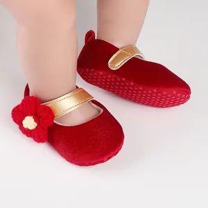 Close-up of red velvet baby girl princess shoes with gold strap and flower detail