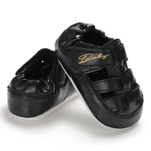 Macro detail of black closed-toe baby sandals with anti-slip sole and gold script