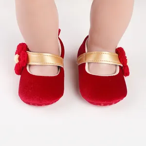 Close-up view of red velvet baby princess walking shoes with gold straps and flower detail
