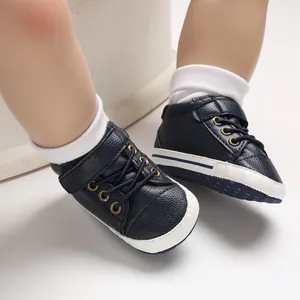 Detail shot of dark blue faux leather high-top baby walking shoes with soft white soles.