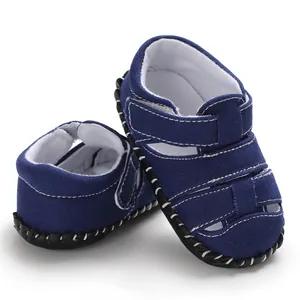 Primo piano di sandali in tela blu scuro per neonati con pratica chiusura in velcro