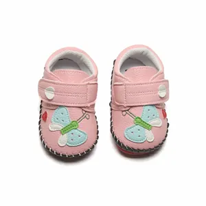 Vue détaillée des chaussures de marche roses pour bébé avec motif papillon brodé.