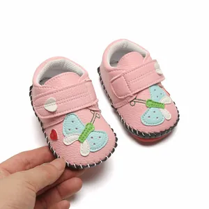 Gros plan de chaussures de marche roses pour bébés avec motifs papillon et cœur.