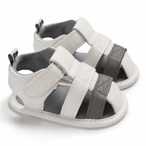 Close-up of white and grey baby summer sandals with soft soles and velcro straps