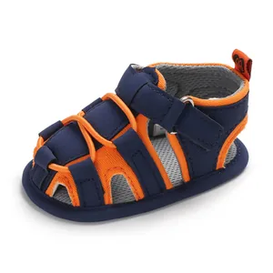 Primo piano dei sandali primi passi per neonati blu navy e arancioni con suola morbida.